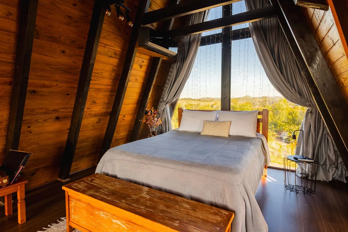 Does 8 Sleep work in the fall? A-frame cabin bedroom with a big window on a cool autumn night